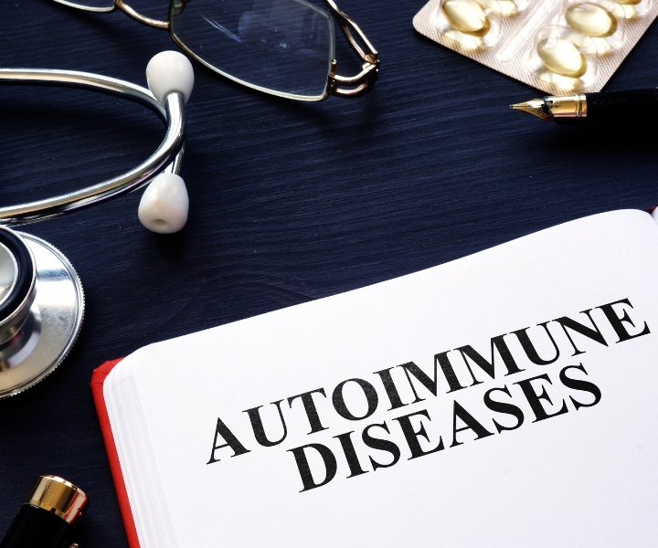 Notebook with text "Autoimmune Diseases" near stethoscope and pills.